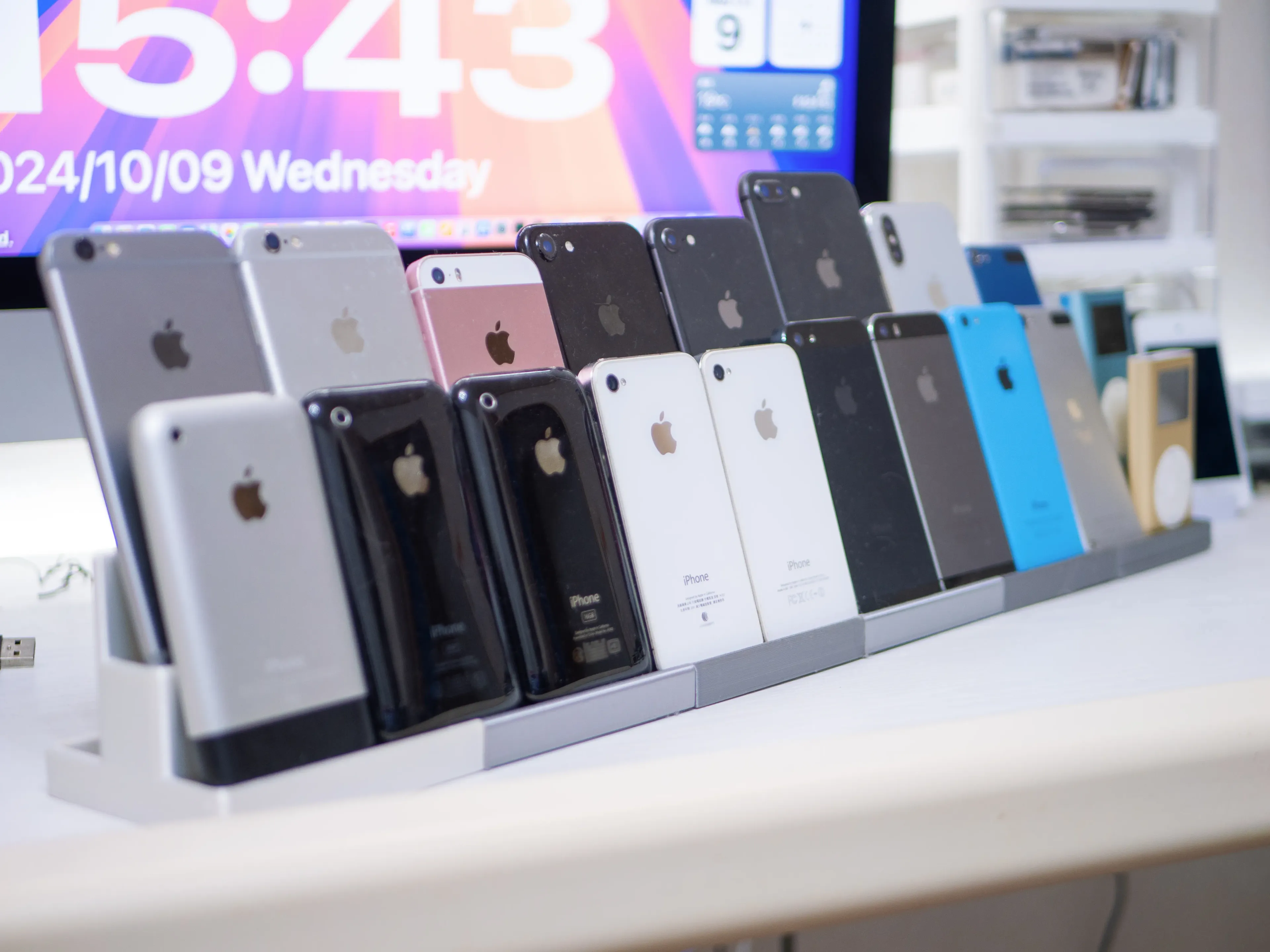 様々な世代のiPhoneがスタンドに立て掛けられている画像